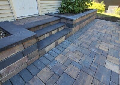 Beautifully paved stone steps leading to a doorway, with a matching stone wall and patio.