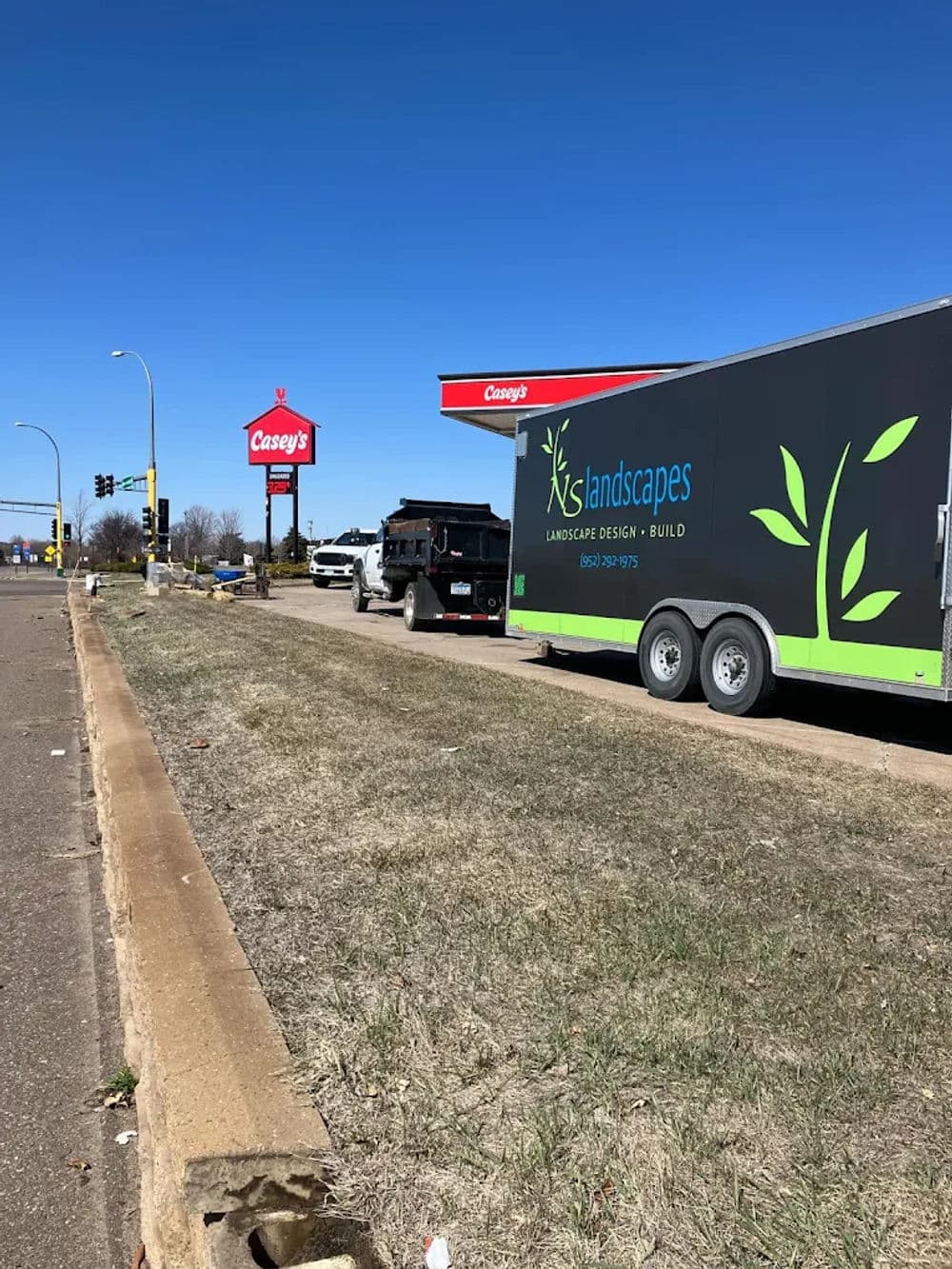 Landscape design trailer parked near Casey's gas station on a sunny day.