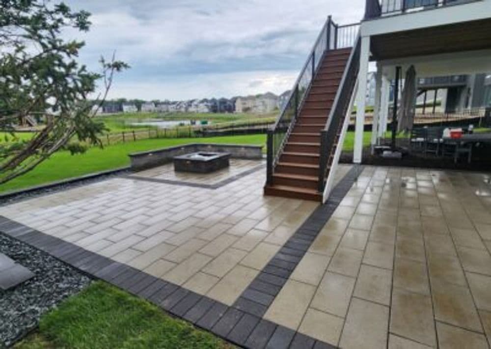 paved patio with fire pit, stairs leading to upper deck, green landscape backdrop