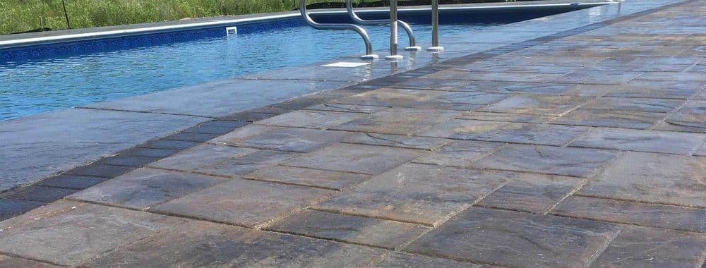 Poolside view showcasing slate tiles and a sparkling blue swimming pool.