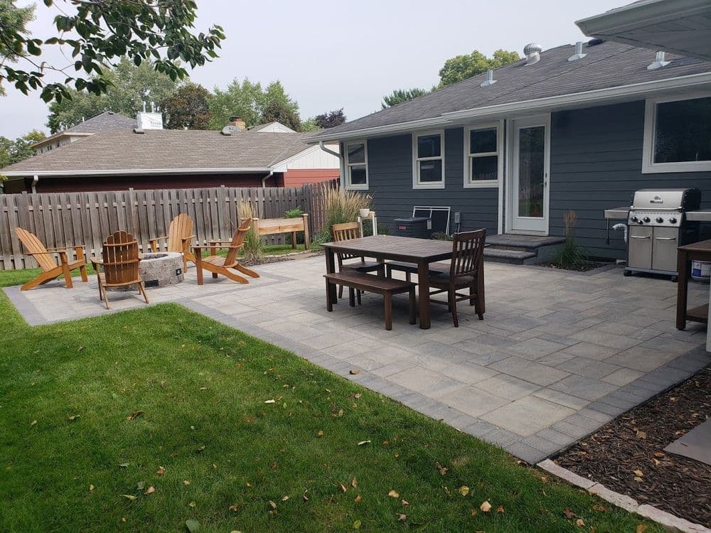 Outdoor patio with seating, grill, and landscaped garden area in a residential backyard.