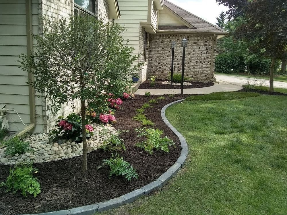 Beautifully landscaped front yard with flowering shrubs, mulch, and decorative rocks.