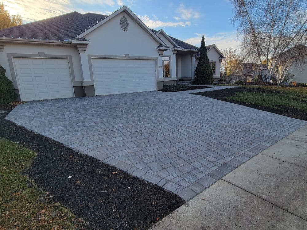Paved driveway and garage with modern home and landscaped yard in suburban setting.