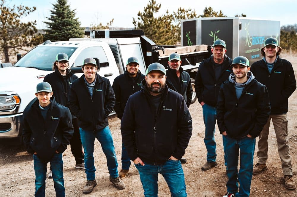 Landscape team posing in front of a truck, showcasing their professional services outdoors.