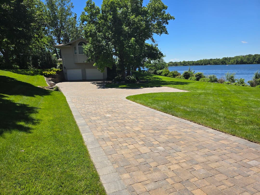 Scenic driveway leading to a lakefront house surrounded by lush green trees.