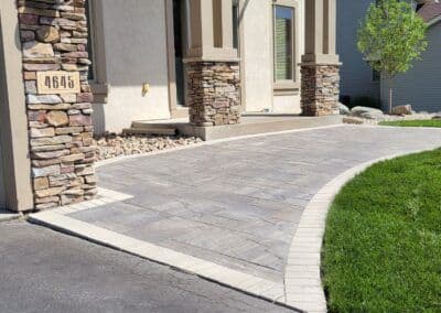 Stylish stone pathway and landscaped entrance of a home with a grassy lawn.
